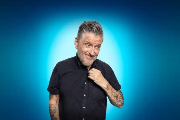 Craig Ferguson standing in front of a blue backdrop